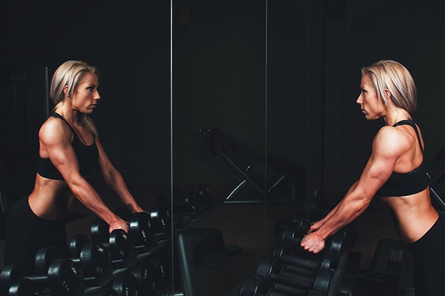 woman lifting weights and looking in mirror